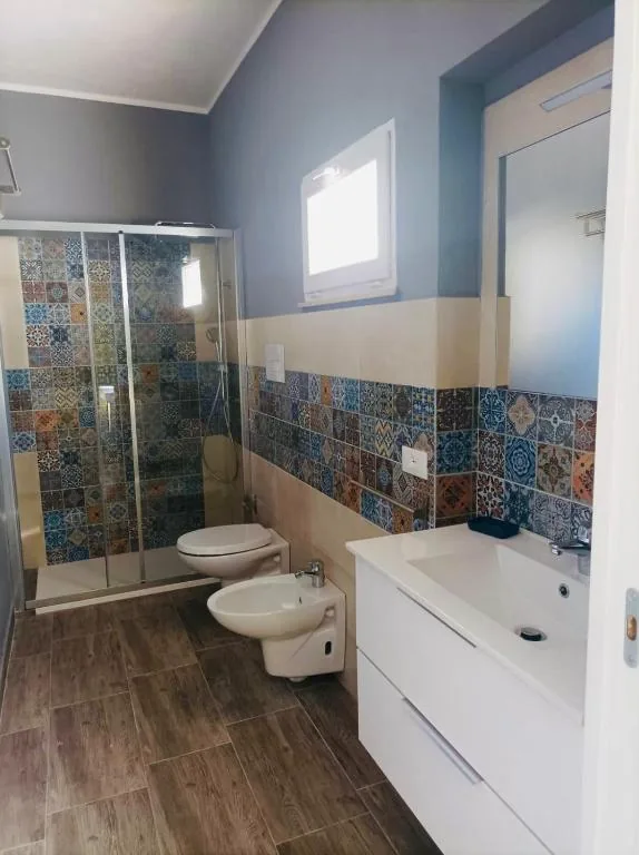Bagno con doccia in vetro e piastrelle decorate