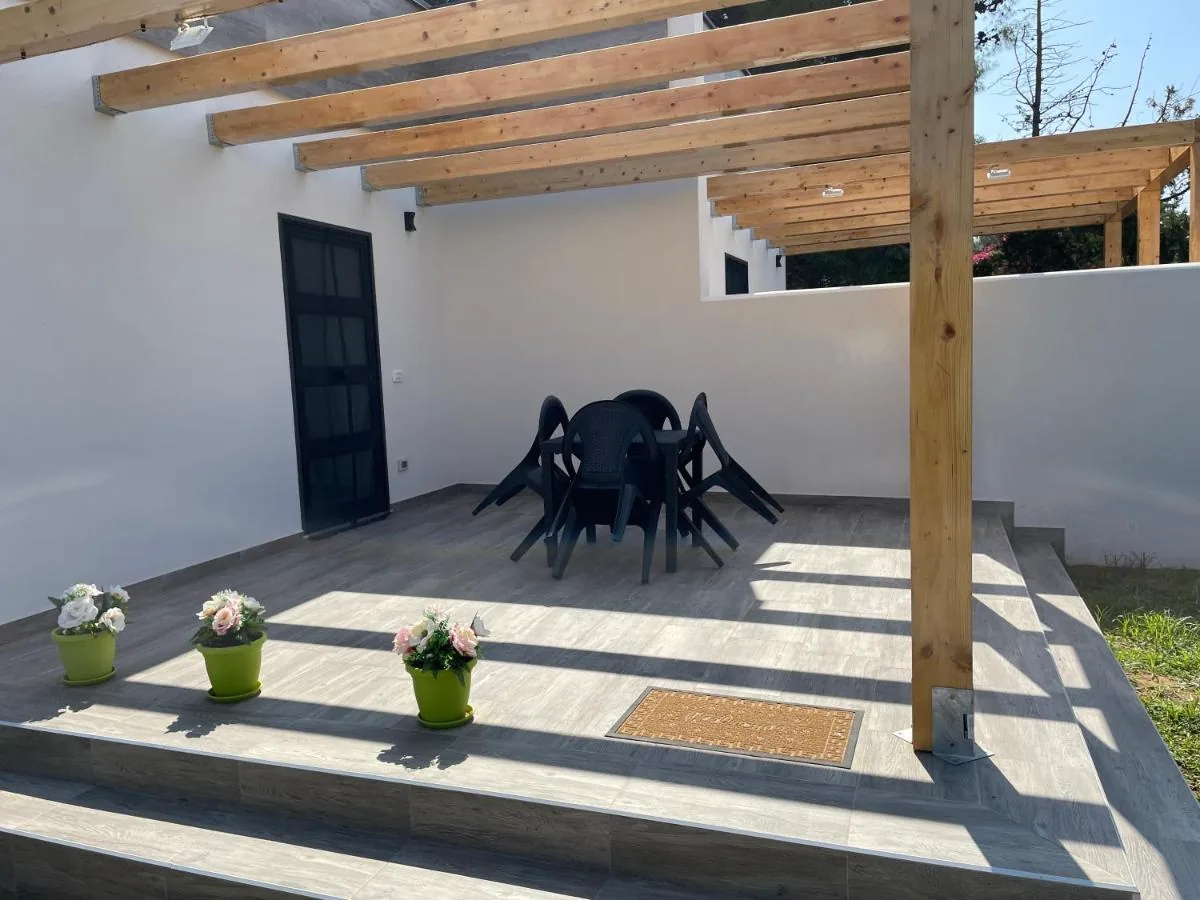 Veranda con pergolato in legno, tavolo e sedie, e vasi di fiori